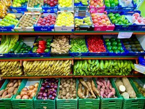 Mostrador con diversas frutas y verduras (cebollas, patatas, yuca, calabacin, jengibre, aguacate)